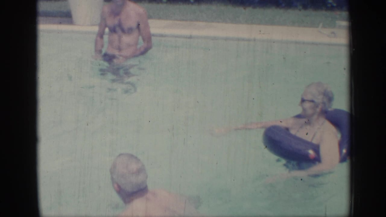 Adults in a swimming pool, with a woman on a float and men nearby.