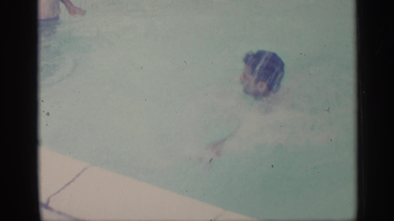 Swimmer seen from above in pale blue pool water near the pool edge.