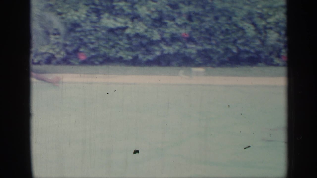 Pool water and hedges with a man partly visible near the left edge.
