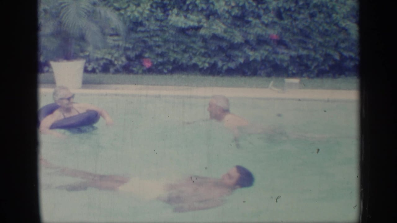 Adults in a swimming pool, including a woman leaning on a dark inflatable ring.