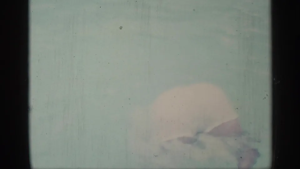Soft 8mm frame from the Indiana pool footage showing a swimmer bent low or partly underwater in pale pool water.