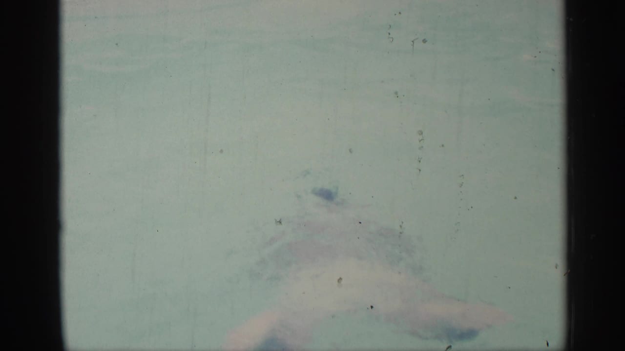 Swimmer partly submerged in pale pool water with motion blur.