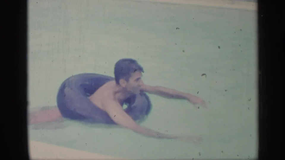 In the 1959 Indiana pool scene, the man floats on a dark inner tube with one arm extended into the water.