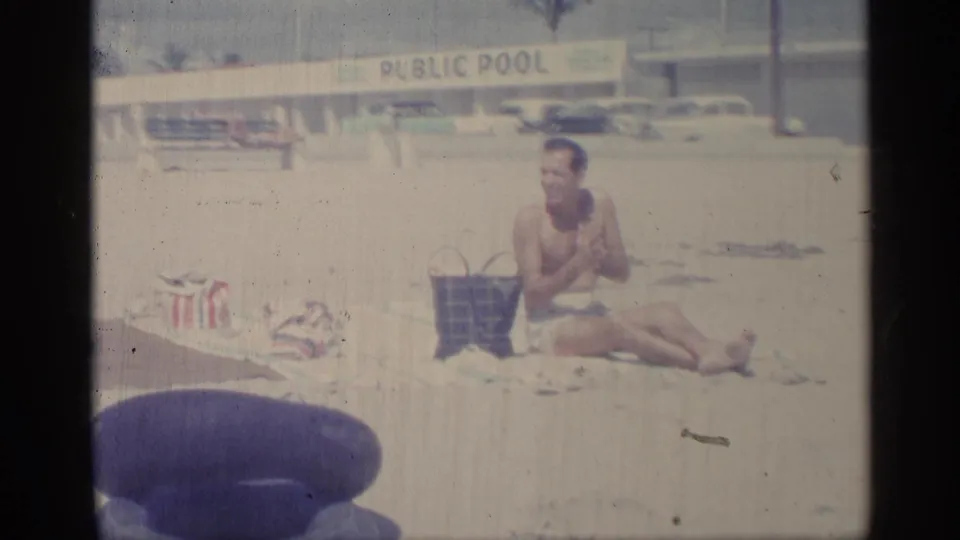 The closing frame shows a seated beachgoer beside a bag, with the public pool sign, parked cars, and pale 8mm exposure in the background.