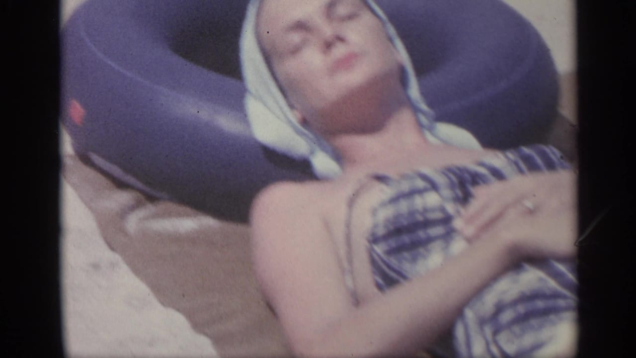 Close view of a woman sunbathing on sand beside a purple inner tube.