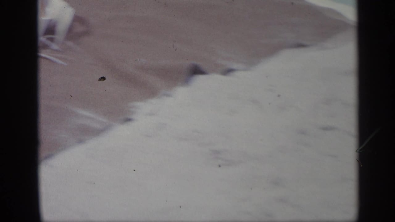 Close cropped view of a person lying on a striped towel with pale cloth in the foreground.