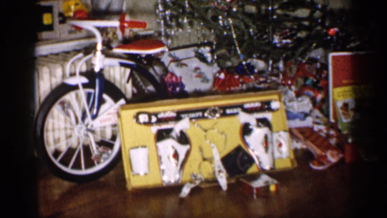 1959 Michigan holiday interior with a bicycle, boxed toy set, ornaments, tinsel, and gifts arranged under the tree.