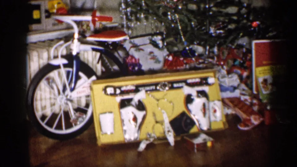 1959 Michigan holiday interior with a bicycle, boxed toy set, ornaments, tinsel, and gifts arranged under the tree.