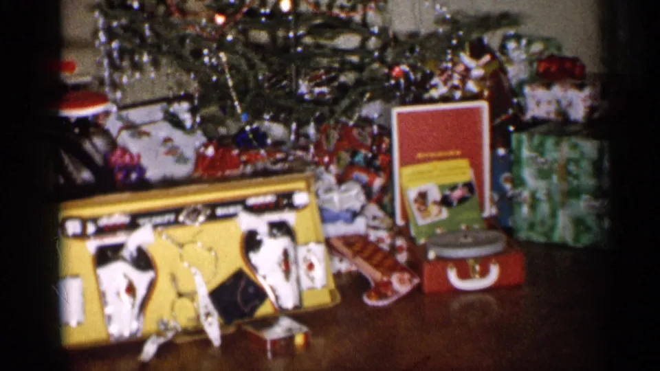 1959 Michigan 8mm frame showing presents under a Christmas tree with a yellow toy cash register and red suitcase-style record player.