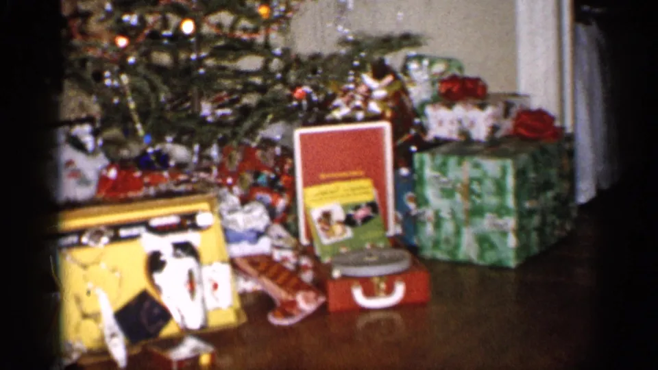 1959 Michigan 8mm view of a toy cash register, record player, and wrapped presents beneath a decorated Christmas tree.