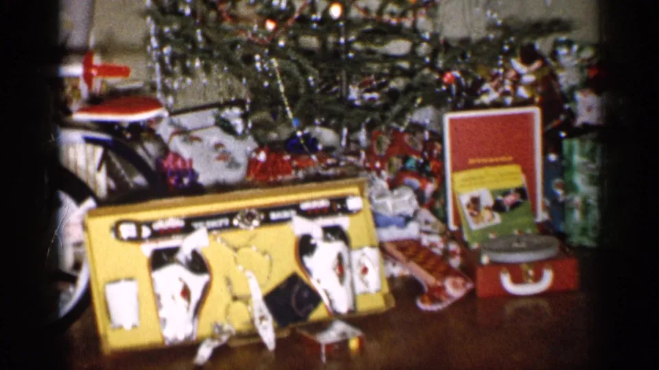 1959 Michigan frame showing a Christmas gift display with a yellow toy cash register, red record player, wrapped boxes, and tree tinsel.