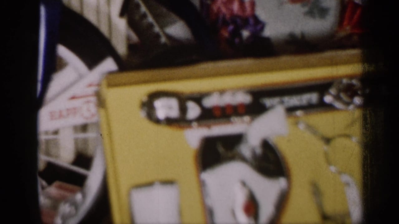 1959 Michigan home-movie frame showing boxed toys and a partial bicycle near a radiator in soft 8mm focus.