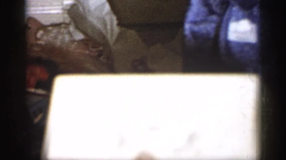 1959 Michigan 8mm frame showing toy bicycle parts near a white box and fabric on a wooden floor.