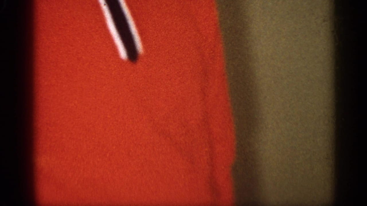 Close-up of red fabric or clothing within the soft handheld 8mm frame, with little surrounding context visible.