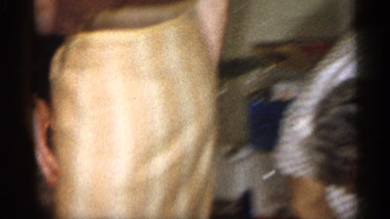 Blurred close view of women bending indoors near furniture and household items.