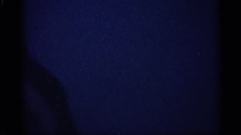 Underexposed 8mm frame with blue color cast and dark gate edges from the Michigan 1959 home-movie clip.