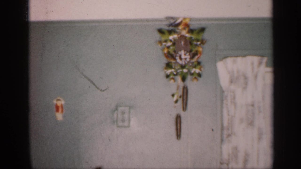 Cuckoo clock on a pale green wall beside a curtained opening.