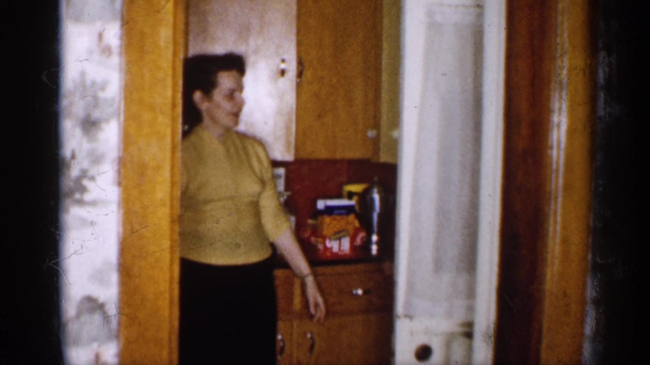 Woman in yellow sweater reaches toward a kitchen cabinet with packaged items nearby.