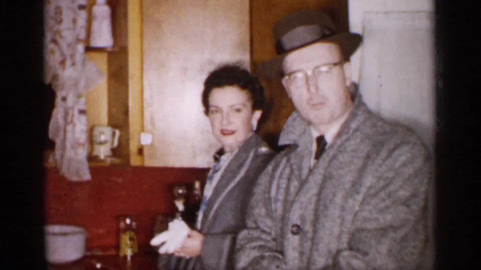 The couple stands close in a 1959 Michigan kitchen, with the man facing the camera and the woman smiling slightly.