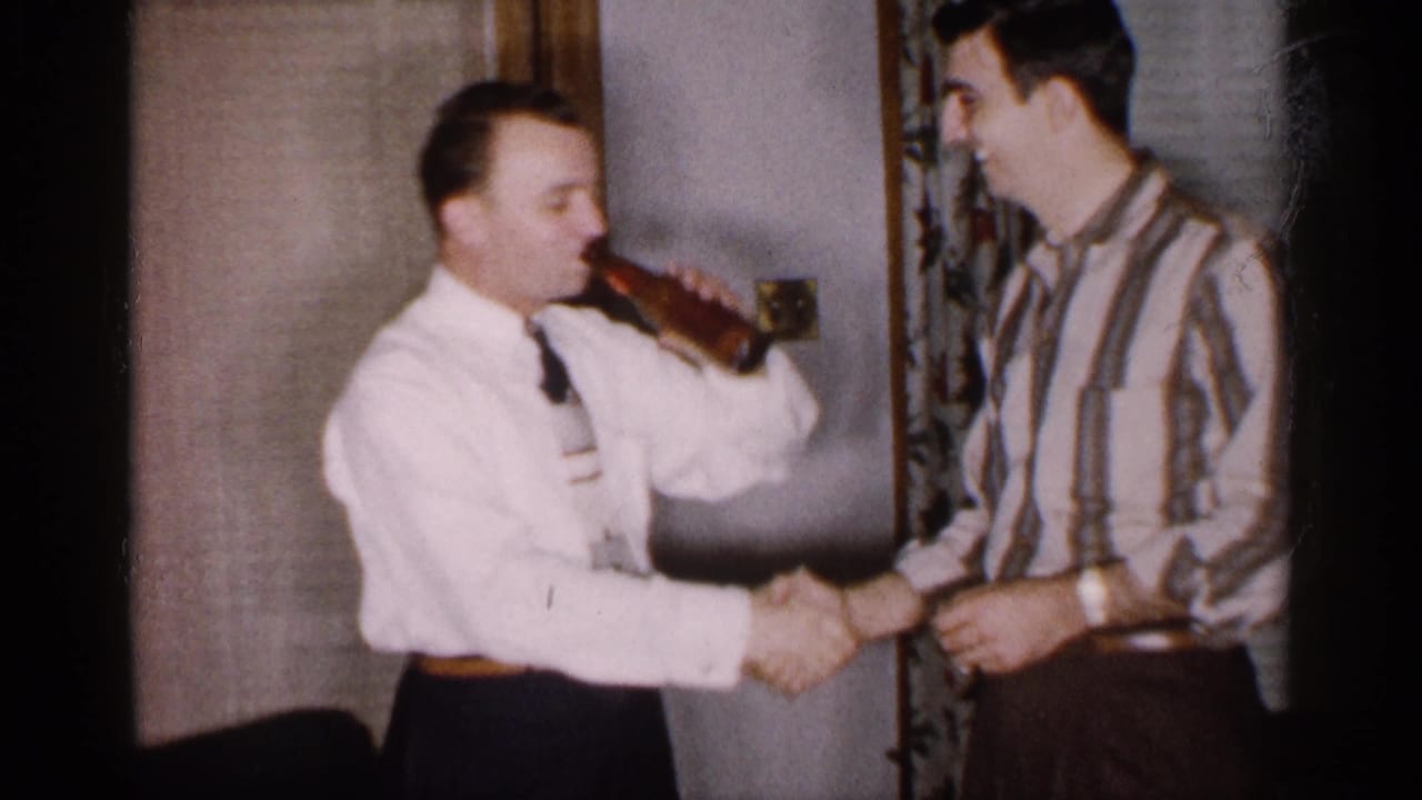 The man in the white shirt and tie drinks from the bottle while shaking hands with a smiling man in a striped shirt.