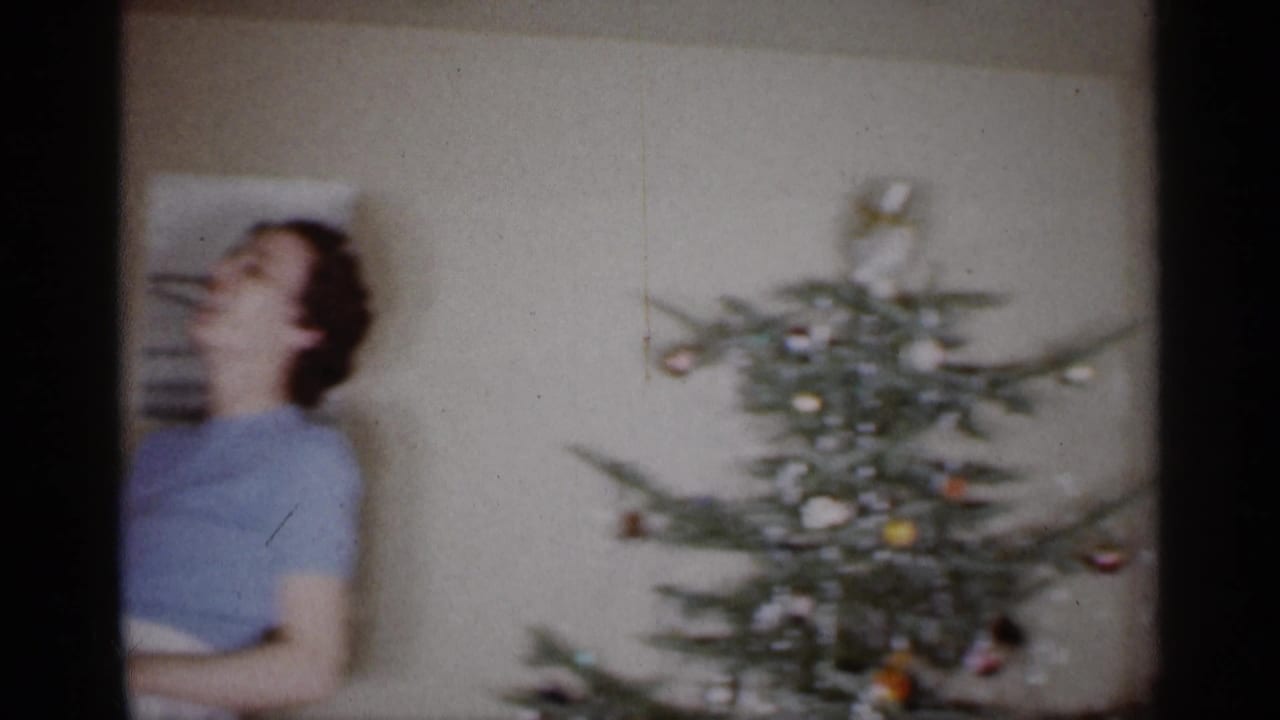 Woman near a decorated Christmas tree inside a living room.