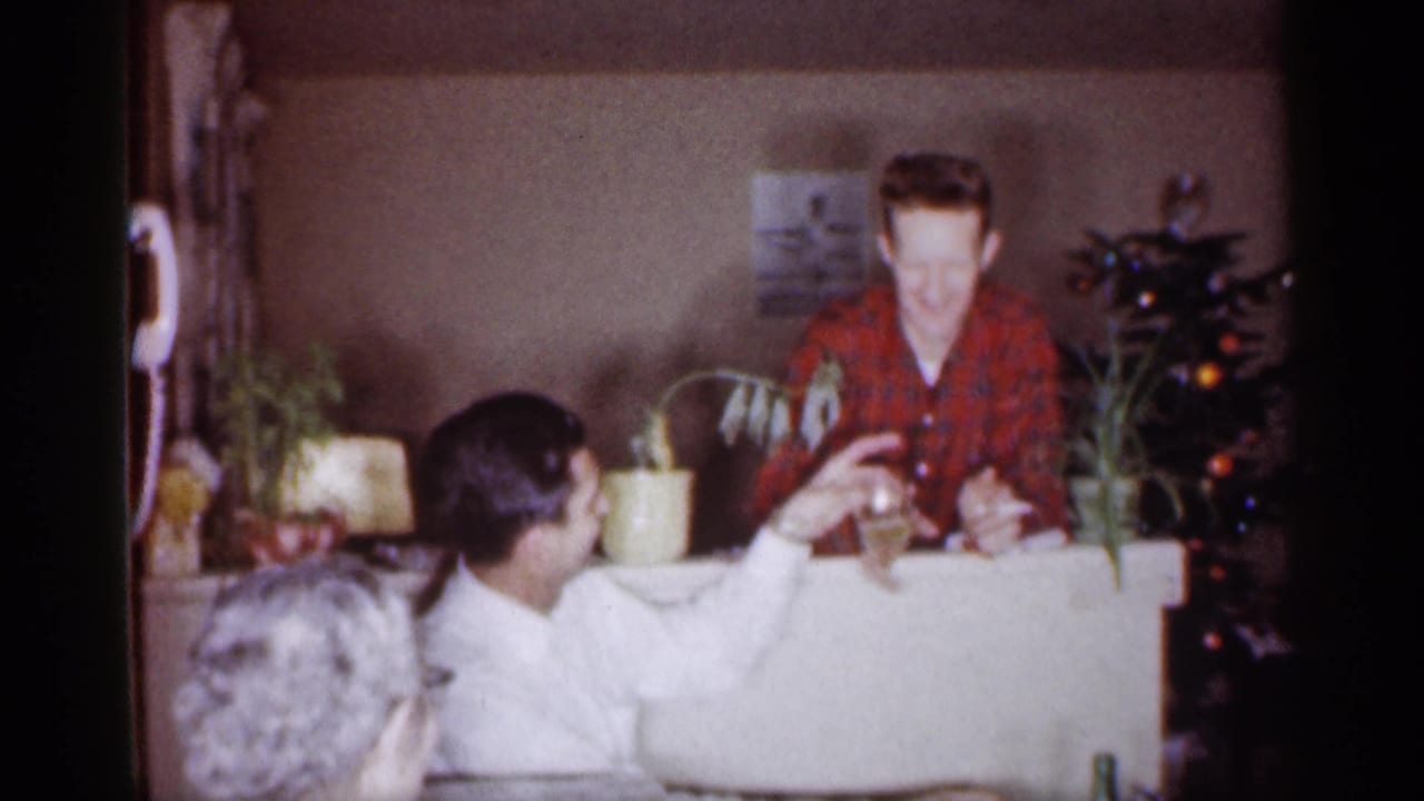 Man in a white shirt reaches toward a man in a red plaid shirt with a glass.