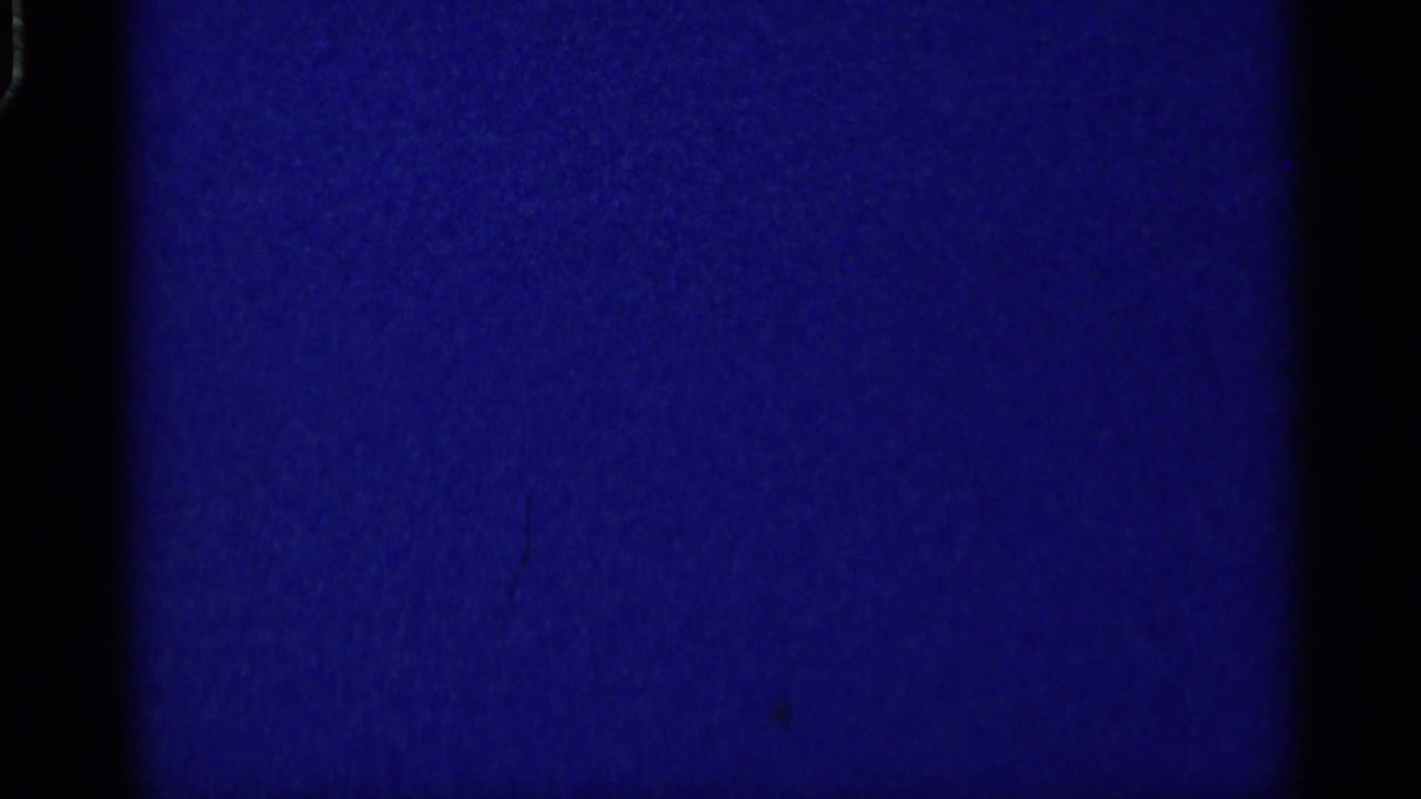 Blue-tinted blank or underexposed film frame with dark vertical borders and grain.
