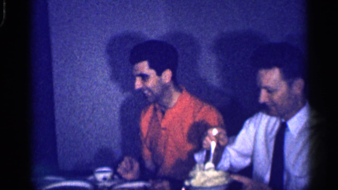A man in a white shirt serves mashed potatoes beside another man in an orange shirt.