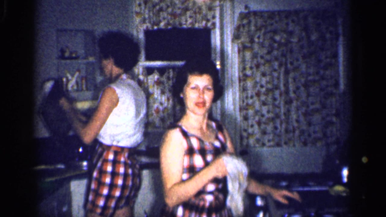 In the Michigan kitchen, one woman smiles toward the camera with a cloth while another stands at the counter.