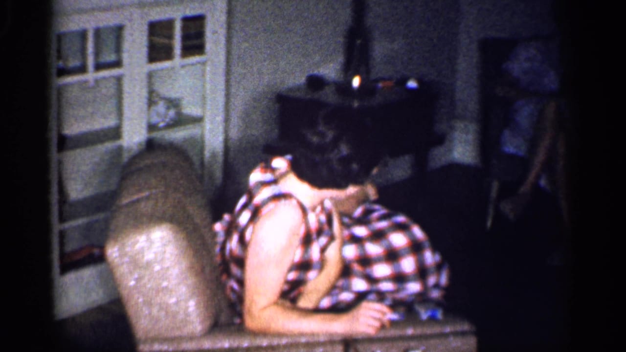 1959 Michigan indoor frame showing a woman in a checkered dress reclining while another woman sits near a cabinet.