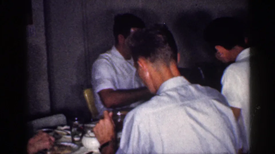 Adults remain seated around the dining table in a dim Michigan interior during the 1959 family meal.