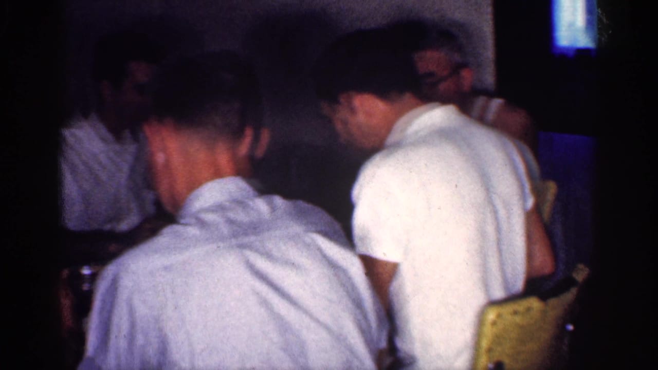 Adult men seated around a dim dining table in a private interior.