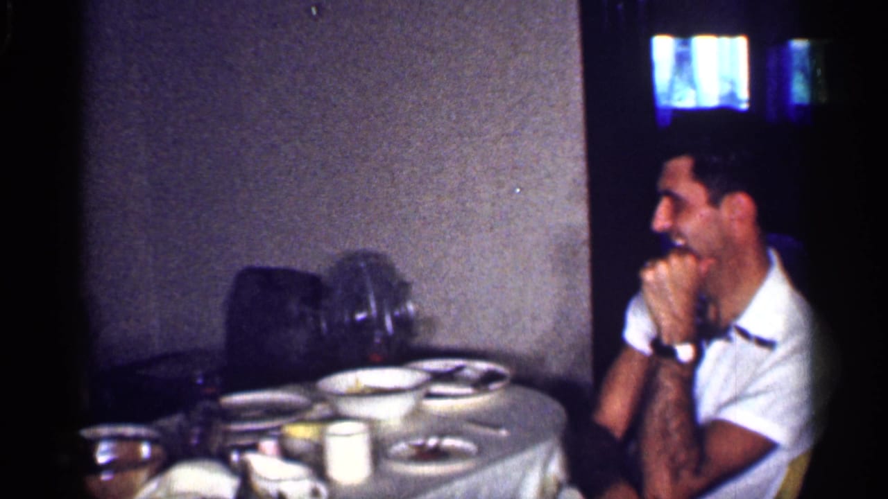Man laughs with his hands near his face beside a table with dishes.