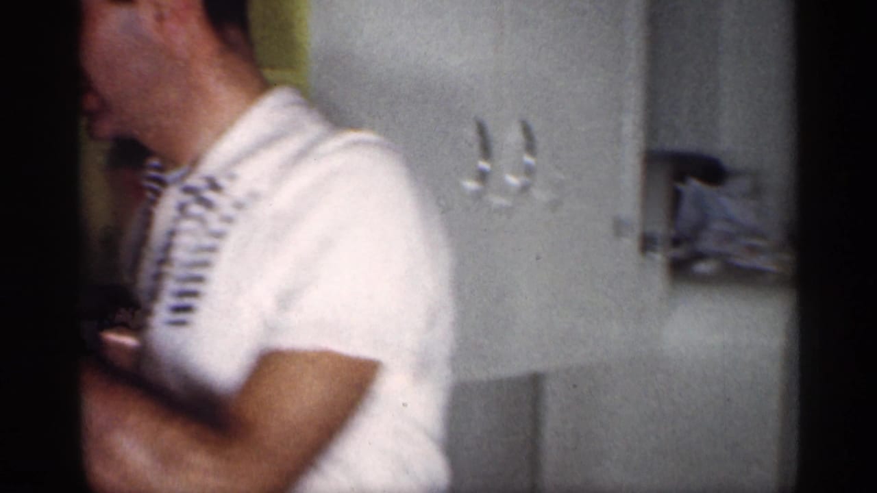 A man in a white shirt moves through a Michigan kitchen with cabinets, refrigerator, and wall hooks visible.