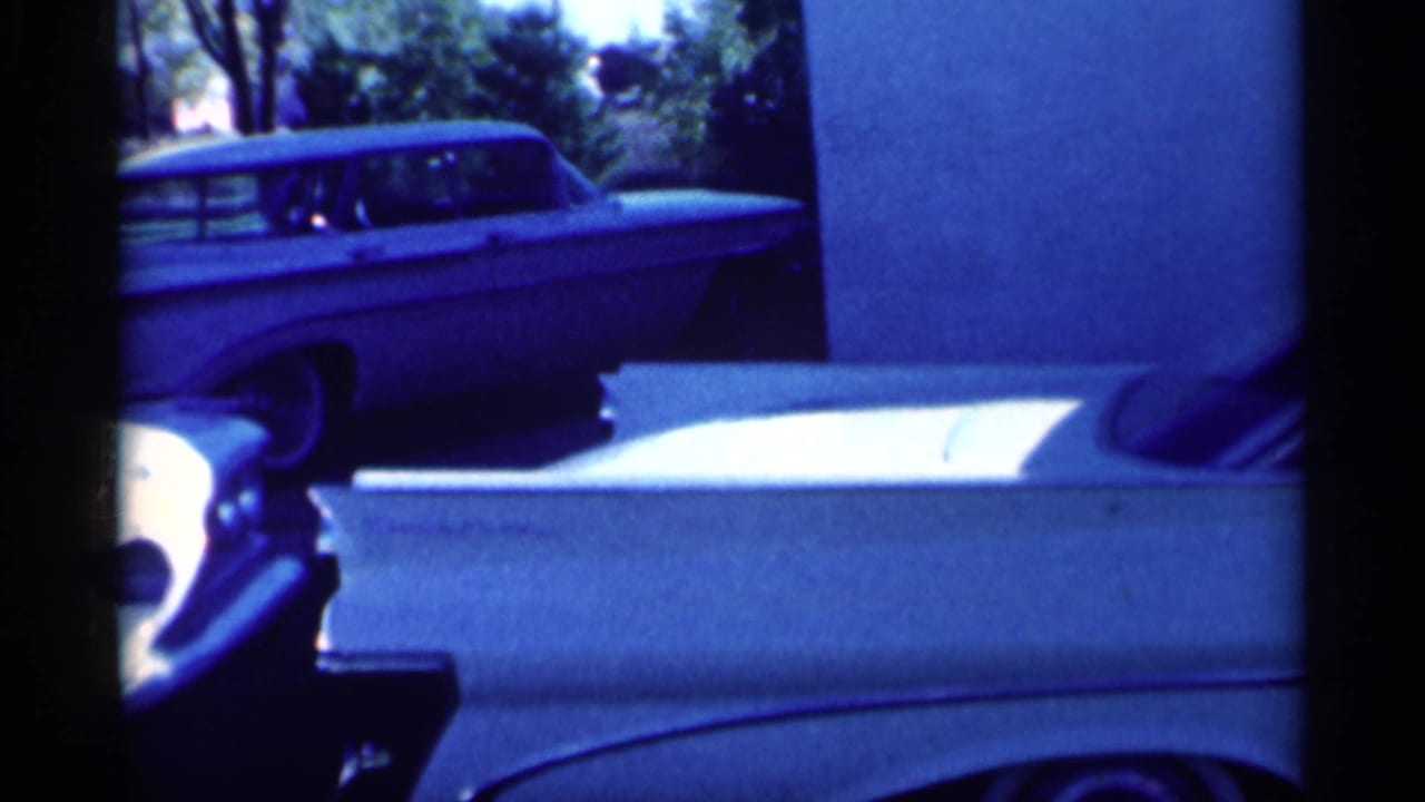 Light station wagon and white sedan parked beside a suburban lawn.