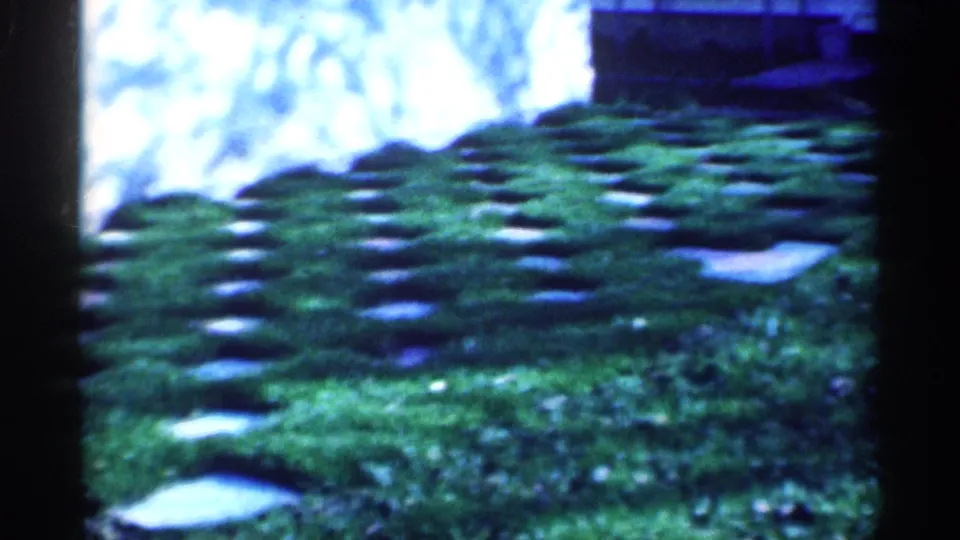 1959 Michigan 8mm frame showing the lawn and inset pavers from a slightly shifted handheld viewpoint.