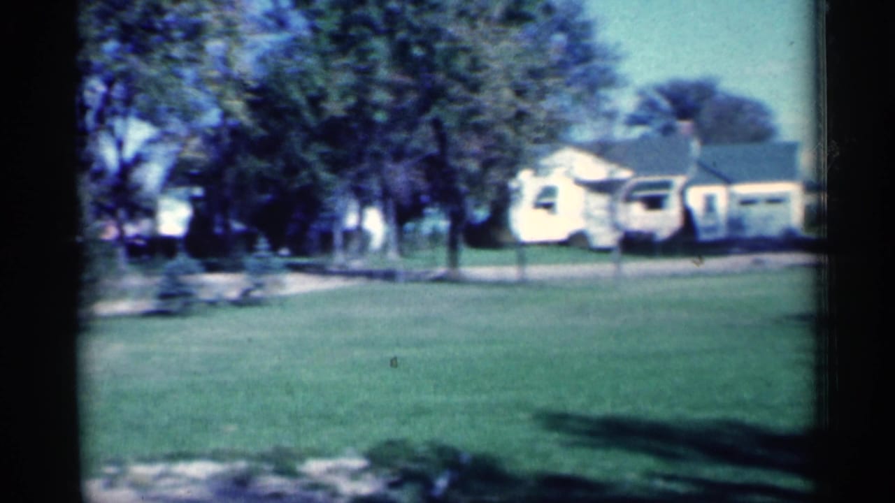 Grassy lawn facing small houses and trees across a residential street.