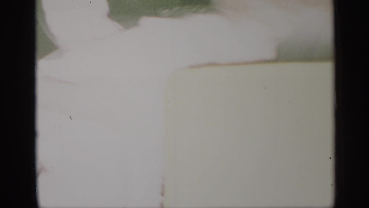 Soft, overexposed 1959 New York home-movie frame with an interior doorway and a partly cropped person.