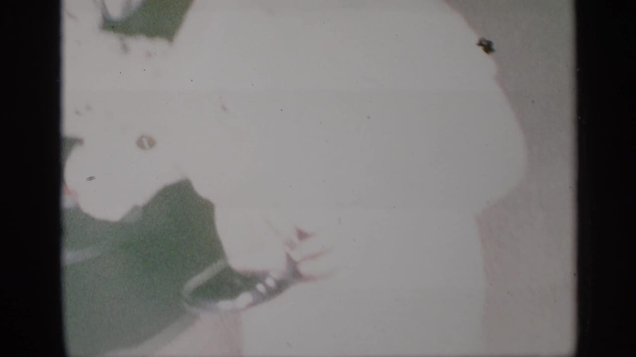 Overexposed 8mm frame of a child moving indoors near a dark vertical edge.
