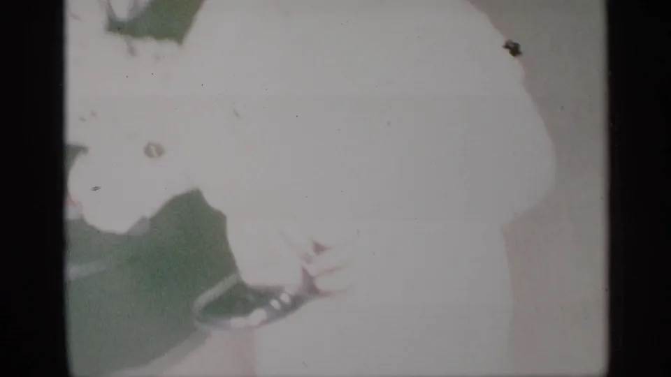 1959 New York 8mm home-movie frame showing a child in light clothing moving in a softly lit room.