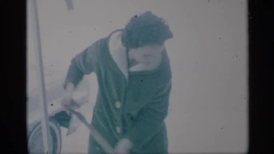 The final frame shows the woman bending over the shovel in snowy 1959 New York footage, with soft focus and film specks visible.