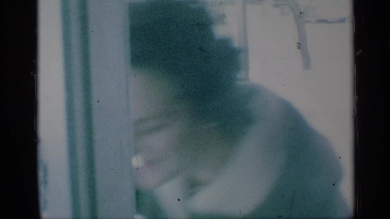 Blurred person in dark clothing near the camera beside pale vertical edges.
