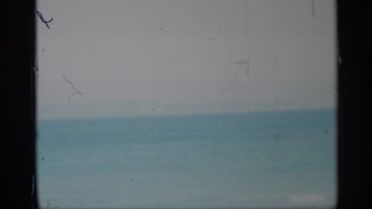 Hazy blue sea and sky seen between dark vertical frame edges.