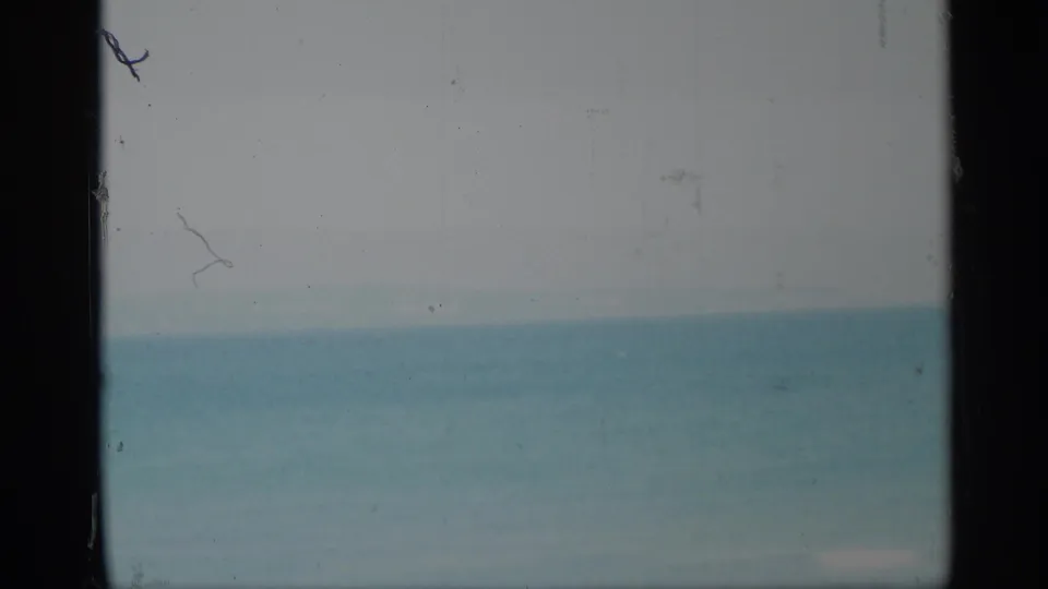 1959 New York 8mm frame showing a soft, hazy seascape viewed through dark vertical framing edges.