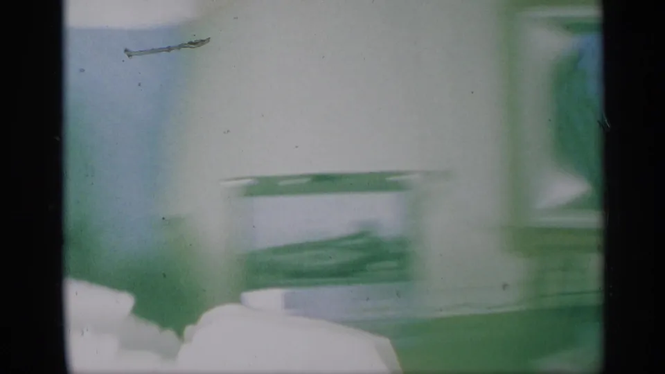 Soft 8mm frame from a New York home interior with a blurred green Christmas tree and light household surfaces.