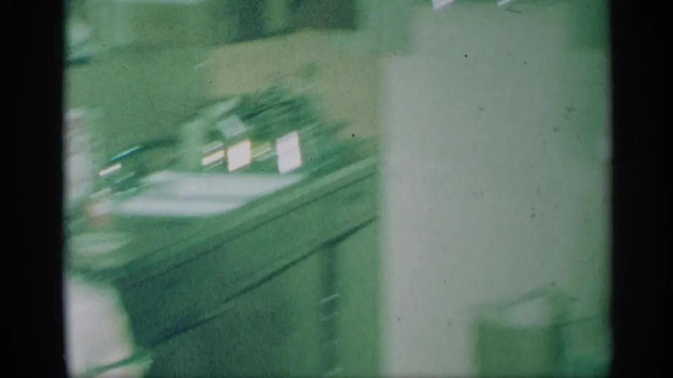 1959 New York home-movie frame showing a blurred kitchen counter, cabinets, and wall area in a private interior.