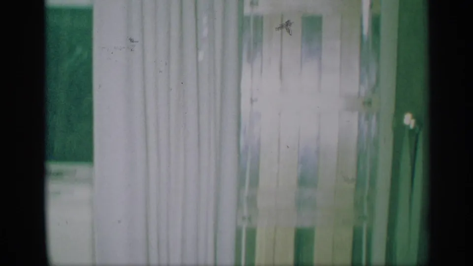 1959 New York home-movie frame showing pale curtains and vertical kitchen interior details in soft, overexposed 8mm color.
