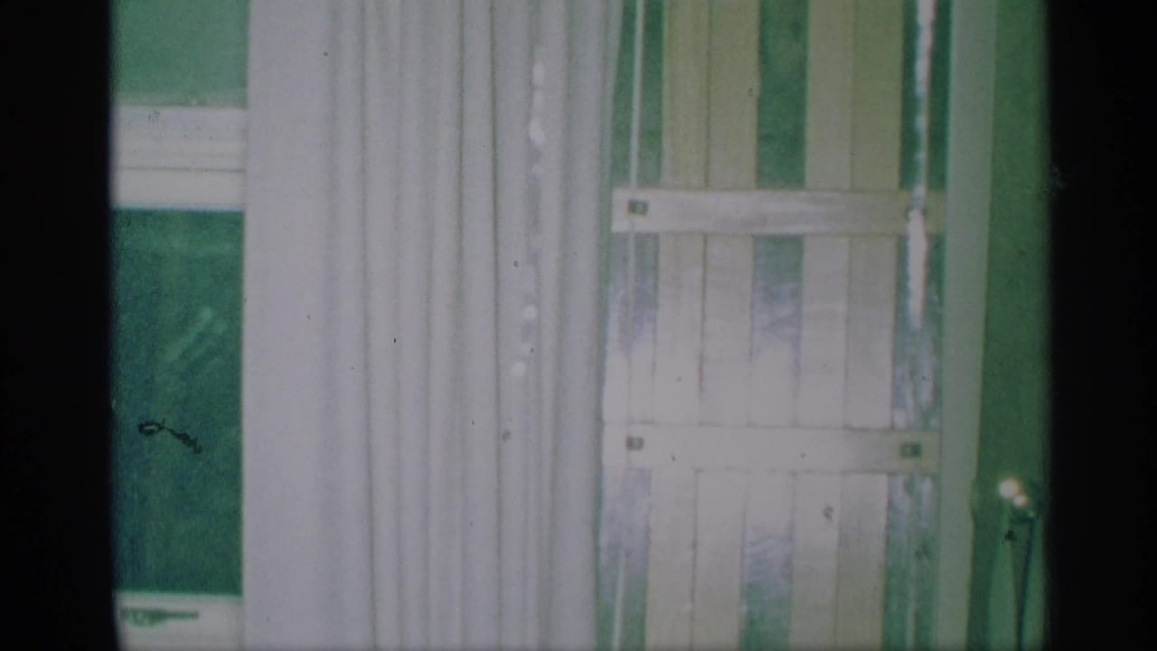 White curtains and green blinds beside a window in a private room.