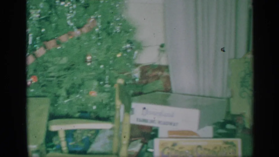 1959 New York home interior with a Christmas tree, window curtains, wrapped items, and holiday cards or packages near the base.