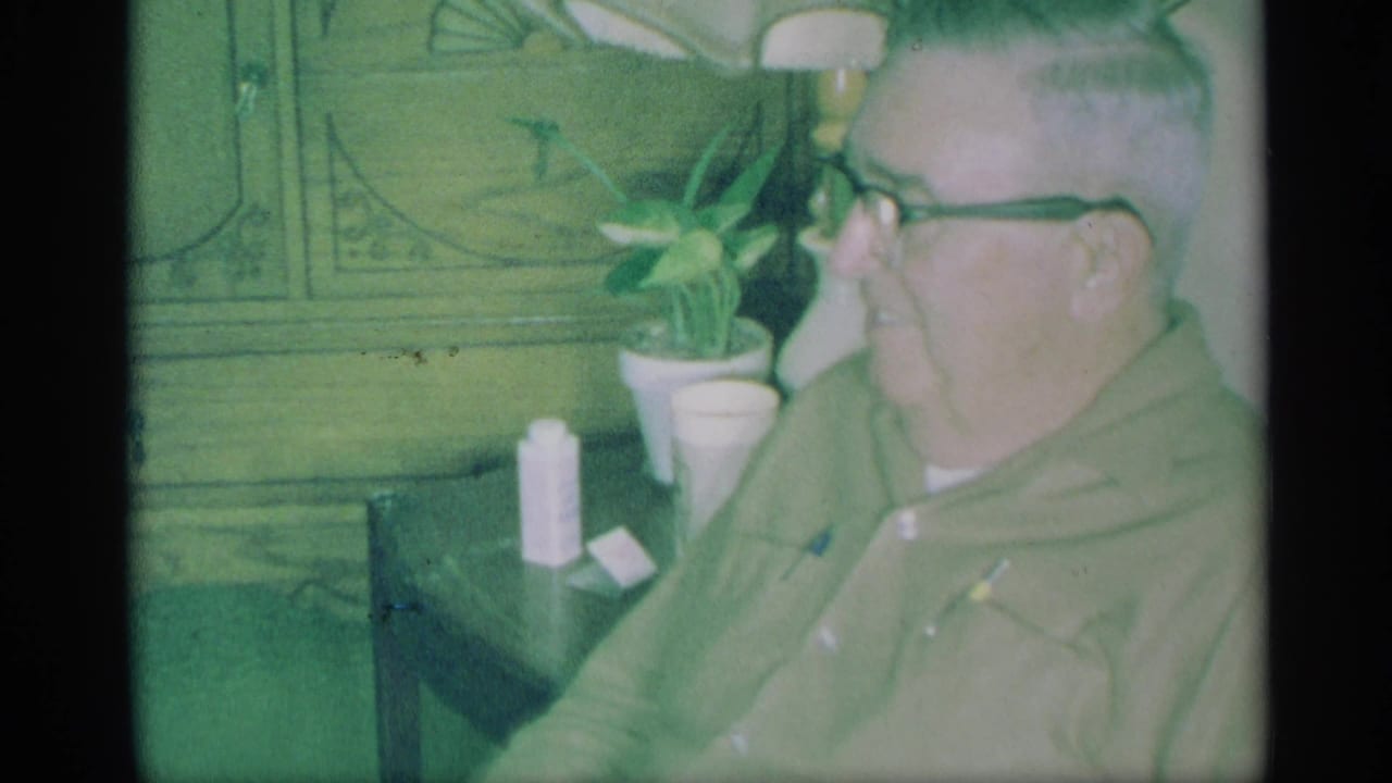 Man wearing glasses seated beside a table in a private living room.